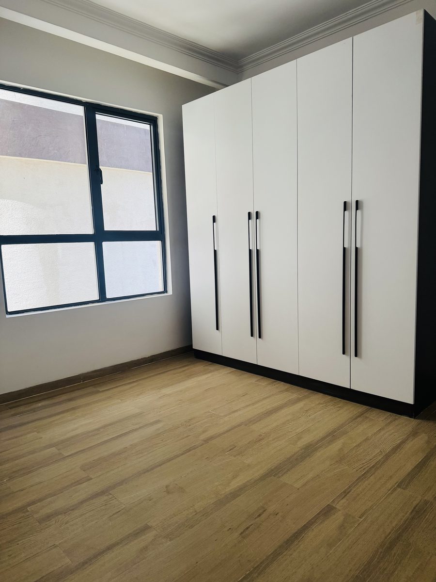 Empty bedroom with fitted white wardrobes